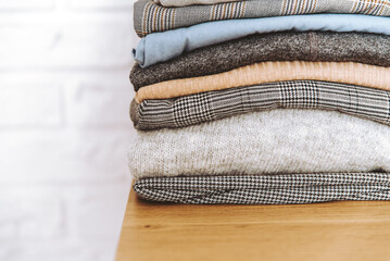 Wall Mural - Stack of folded casual clothes on table with copy space. Pile of cotton clothes and sweaters.