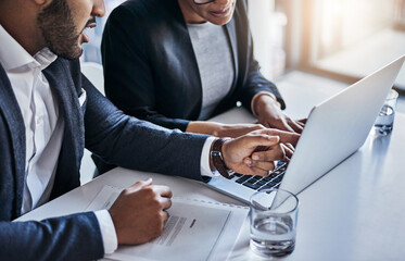 Technology improves the quality of their work. Shot of two businesspeople working together on a laptop in an office.