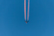 Flugzeug an einem blauen wolkenlosen Himmel mit farbigen bunten Kondensstreifen ohne Wolken während Sonnenuntergang und goldenen Stunde, Deutschland