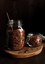 Big And Small Jars With Homemade Granola On The Wooden Serving Desk