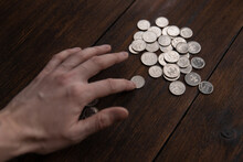 A Man Counts Ruble Coins On A Dark Wooden Background