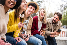Group Of Young People Laughing Out Loud Sitting Outside - Happy Multiracial Students Having Fun Together In College Campus - Friendship Concept With Teenagers Enjoying Day Out On City Street