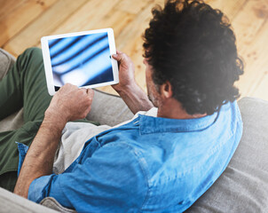 Sticker - Wifi all weekend long. Rearview shot of a bachelor relaxing on the sofa with his tablet.