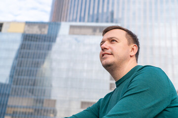 Happy millennial caucasian businessman confident portrait on urban cityscape. Portrait of smiling man standing outside office building with city skyline in background