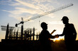 © เลิศลักษณ์ ทิพชัย - silhouettes of construction engineers or managers and construction workers on a construction site shake hands to agree on a work plan Design projects of houses and industrial buildings