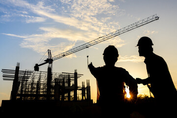 Construction engineer team silhouette talking to managers and construction workers at a construction site. Quality inspection, work plan, home and industrial building design project