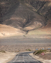 View Of An Endless Road Crossing The Mountains And The Desert Valley In Lanzarote, Canary Islands, Spain.