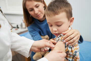 doctor placing medical plaster on child arm after vaccination