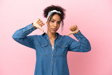 Sticker - Young latin woman isolated on pink background showing thumb down with two hands