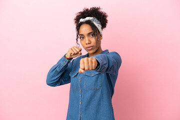 Wall Mural - Young latin woman isolated on pink background with fighting gesture