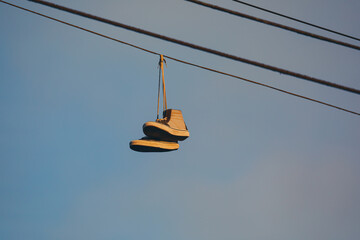 Close up of old sneakers hanging on a power line in the evening glow