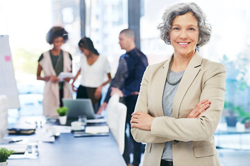 Wall Mural - Im taking my team to the top. Portrait of a businesswoman standing in an office with her colleagues in the background.