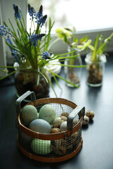 Wall Mural - Christian holiday, Easter. Colored eggs in a basket, a grid on the table. Spring flowers, atmosphere, willow branches in the kitchen. Rustic. Background image, copy space