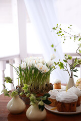 Wall Mural - Christian holiday, Easter. Baking with white icing with a candle. Easter cake. Festive table setting: flowers, glasses, colored eggs. Spring atmosphere, outdoor. Rustic. Background image, copy space