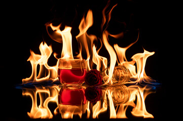 Alcoholic drink Whiskey with a glass on its side on a reflective surface with beautiful orange flames behind it and a blue start point with flames flowing upwards