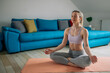 © Zamrznuti tonovi - Woman siting in a lotus yoga position on the fitness mat at home