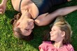 Happy mom daughter child lying on green grass, top view.