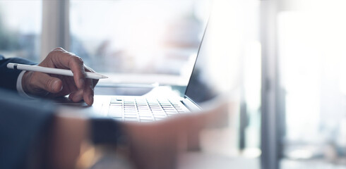 Close of businessman working on laptop computer at modern office, business background