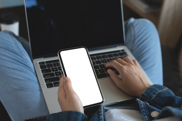 Poster - Cell phone and laptop computer mockup, young casual woman in blue jeans sitting on sofa using blank screen mobile phone and laptop computer at home