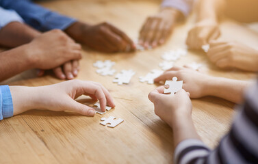 Poster - Jigsaw solutions. Shot of a group of people building a puzzle together.