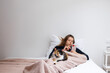 © KIFOR PRODUCTION - Pets, morning, comfort, vacation and people concept - young woman looking at phone and she has a tricolor cat sitting on her feet.