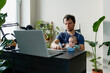© Елена Григорович - Adult man father working home office with baby boy and laptop computer. multi-tasking, freelance and fatherhood concept.