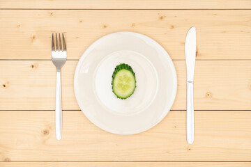 The concept of diet and healthy eating. One slice of fresh green cucumber on a white plate