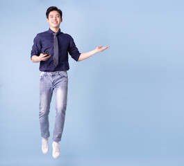 Full length image of young Asian businessman on blue background