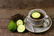 Bergamot tea or Earl Grey tea in ceramic cup and fresh bergamot fruit with sliced on brown wooden table.