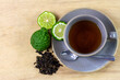 Bergamot tea or Earl Grey tea in ceramic cup and fresh bergamot fruit with sliced on brown wooden table, top view.
