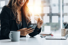 Beautiful Woman Holding A Credit Card, She Uses A Credit Card To Pay For Goods And Services Online, The Concept Of Using A Credit Card For Online Shopping, Ordering Goods And Services On The Website.