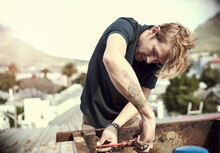 Getting Some Repairs Done. Cropped Shot Of A Handsome Young Man Working Outside On His Roof.