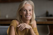 © fizkes - Happy cheerful skinny mature 60s woman home head shot portrait. Middle aged senior lady, pensioner, OAP sitting on sofa, looking at camera with toothy smile, posing, laughing