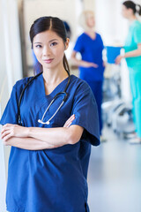 Portrait of Asian Chinese female clinical nurse in scrubs with hospital team