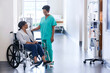 African American nurse in scrubs with medical patient in hospital wheelchair