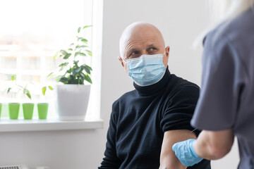 Poster - Young woman doctor injecting vaccine to elderly man during home visit