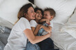 © Natalya - charming mother and her children, daughter and little son have fun at home on the bed