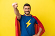 © luismolinero - Young handsome caucasian man isolated on yellow background in superhero costume with proud gesture