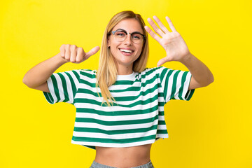 Blonde Uruguayan girl isolated on yellow background counting six with fingers