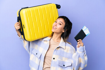 Wall Mural - Young Uruguayan woman over isolated purple background in vacation with suitcase and passport