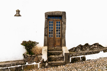 Poster - whitewashed house front with old wooden door set in stone frame on a cobblestone street