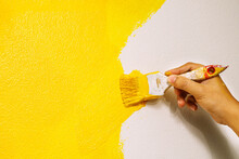 Paint Brush, Close Up Hand Painter Worker Painting On Surface Wall Painting Apartment, Renovating With Yellow Color Paint. Leave Empty Copy Space To Write Descriptive Text Beside.