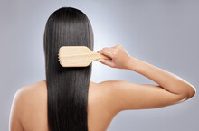 My Is Is Stronger And Healthier. Shot Of A Young Woman Brushing Her Hair While Standing Against A Grey Background.