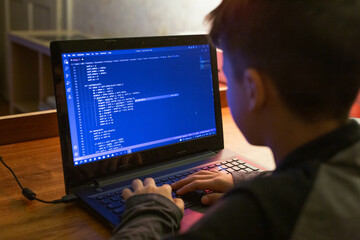 young boy coding on laptop at night