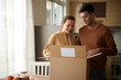 © DragonImages - Happy young husband and wife opening box with belongings in new house they just moved in