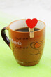 Cup of coffee with wooden clip with red heart
