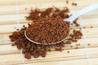 Instant coffee on spoon on bamboo mat, closeup
