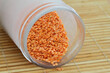 Uncooked red lentils in glass bottle on bamboo mat
