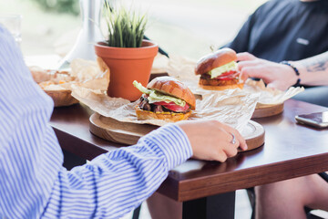 A company of friends met for lunch in a summer cafe, chatting and eating burgers