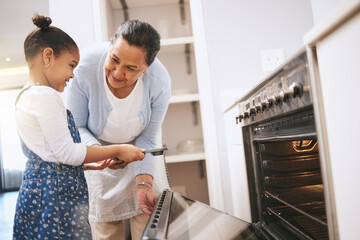 Wall Mural - Dont get too close. Shot of a mature woman helping her grandchild safely open the oven at home.